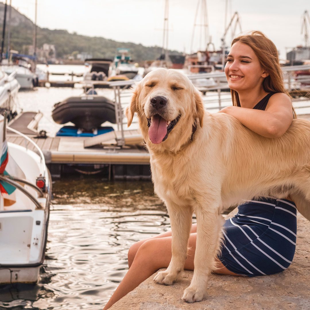 girl sitting on marina dock with her dog
